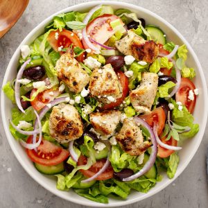 Greek salad with vinaigrette dressing topped with grilled chicken